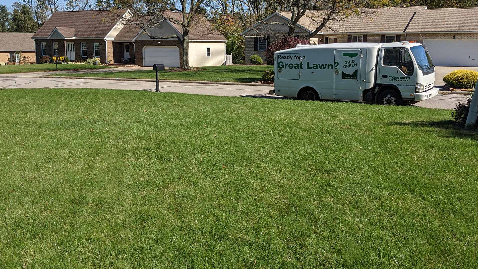 Ohio Green Lawn & Pest service truck by a well-fertilized lawn in Mansfield, OH.